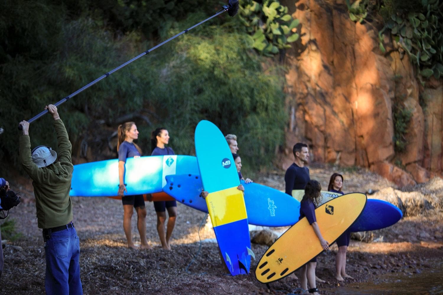 Tournage sur une plage : équipe avec perche et groupe de surfeurs avec planches colorées — placement de marque et production Cinémark
